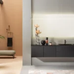 Meuble suspendu Monolite noir avec plan à vasque intégrée, un type de vasque épuré, sous un miroir lumineux
