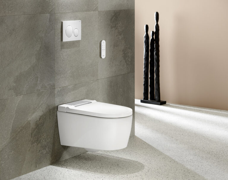 Détartrer un wc lavant : WC lavant suspendu Geberit AquaClean Sela blanc avec télécommande murale devant un mur en pierre gri