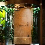 Douche vapeur Gessi Rituale del Vapore : cabine vitrée ronde, paroi en marbre, diffuseur de vapeur au plafond et banc en pier