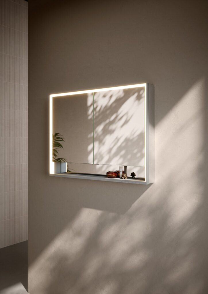 Armoire de toilette à miroir éclairé Keuco Royal Lumos fixée sur un mur beige baigné de lumière naturelle